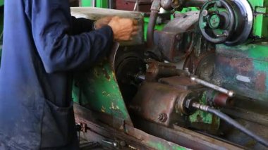 Mavi üniformalı bir işçi eski bir torna torbasının bir parçasını ölçer. Yakın plan.