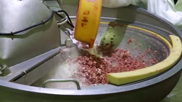 La carne picada se agita automáticamente en un tazón grande. Un aditivo alimentario se vierte en él desde la taza amarilla con guantes y manos. Primer plano — Vídeos de Stock