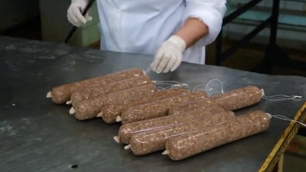 Produção de salsichas. As mãos das mulheres penduram linguiça em uma barra de metal. Close-up — Vídeo de Stock