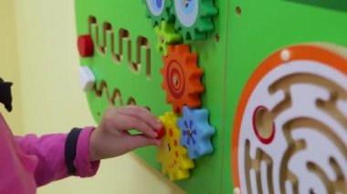 Bebek oyuncak tekerlekleri döndürür. Rakamları değiştiriyor. Duvar oyunu. Meşgul tahtası
