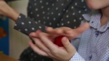 Çocuğun elleri kırmızı topu büker. Yakın plan.