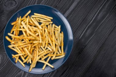 Siyah arka planda mavi tabakta patates kızartması.