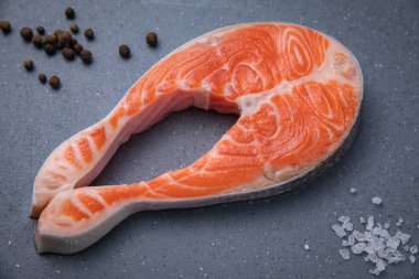 Gri tahtada çiğ somon bifteği ve siyah arka plan