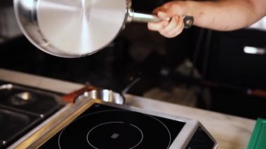 Aşçı tavayı elektrikli ocağa koyar.