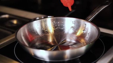 Aşçı tavayı elektrikli ocağa koyar.