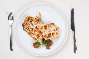 Beyaz tabakta peynir ve domatesli Khachapuri.