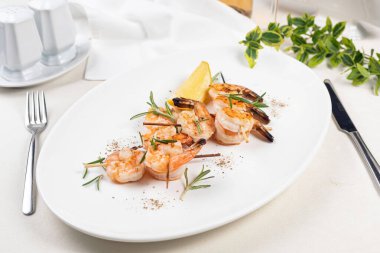 Restoranda beyaz tabakta ızgara karides.