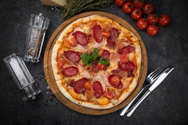 Siyah arka planda domatesli İtalyan pizzası.