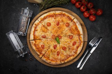 Siyah arka planda domatesli İtalyan pizzası.