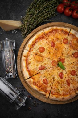 Siyah arka planda domatesli İtalyan pizzası.