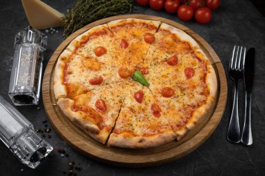 Siyah arka planda domatesli İtalyan pizzası.