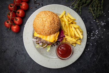 Siyah arka planda patates kızartması ve soslu hamburger.