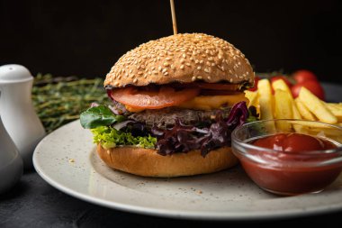 Siyah arka planda patates kızartması ve soslu hamburger.