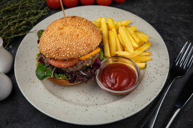 Siyah arka planda patates kızartması ve soslu hamburger.