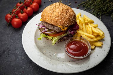 Siyah arka planda patates kızartması ve soslu hamburger.