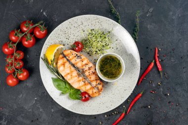 Izgara somon, sos, siyah arka planda domates.