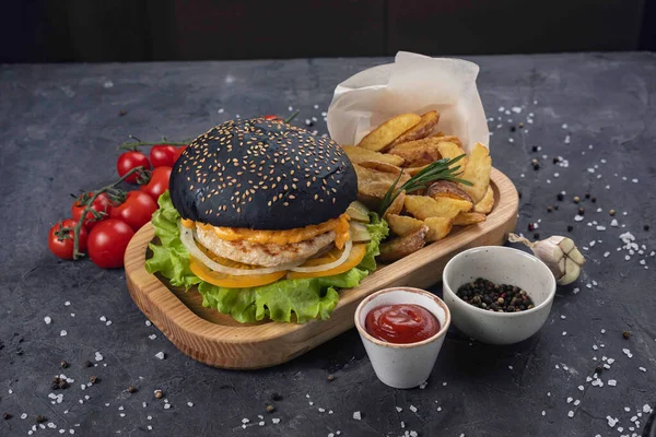 Siyah arka planda patates kızartması ve soslu hamburger.