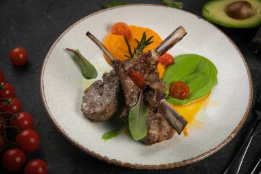 Siyah arka planda beyaz tabakta ızgara kuzu eti.