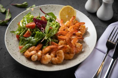 Siyah arka planda salata ve domatesli karides.