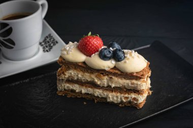 Fransız tatlı Milfey keki, siyah tabakta böğürtlenli.