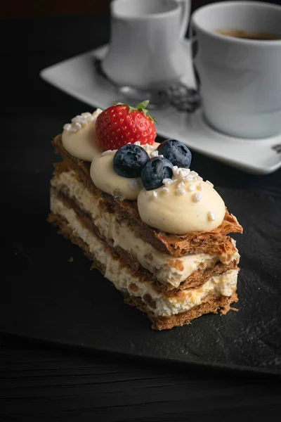 Fransız tatlı Milfey keki, siyah tabakta böğürtlenli.