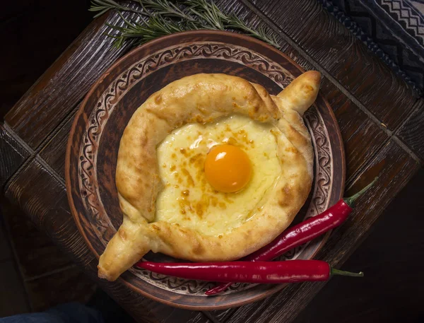 Misafirperver Gürcü mutfağı. Ahşap bir arka planda peynir ve yumurtalı Khachapuri.