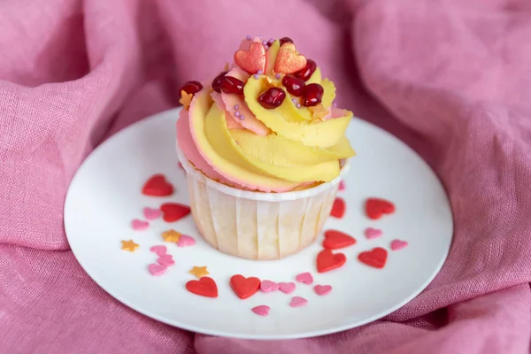  Beyaz tabakta ve pembe arka planda geleneksel limonlu kek. Pembe-sarı tereyağı kremi ve nar tohumlarıyla. Yakın plan.