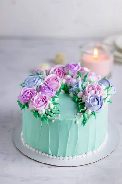 Tasty cake with cream roses for wedding, birthday. Beautiful, fashionable cake. Turquoise on a marble table and with a candle — Stock Photo, Image