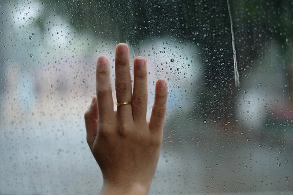 The hand touch the raining drop mirror.the raining drop mirror.  water drop on the mirror. Hope. Waiting time. Lonely.