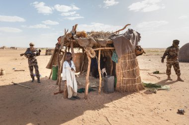 Agadez, Nijer: Nijerya ve Nijerya 'nın pansiyonerlerinden Sahra Çölü' ndeki sığır barınağının önünde asker ve Afrikalı çocuk. 