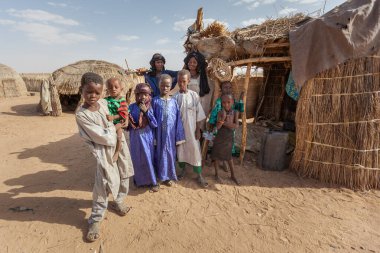 Agadez, Nijer: Nijerya ve Cezayir 'deki pansiyonerlerinin Sahra Çölü' ndeki evlerinin önünde geleneksel renkli giysiler içinde Afrikalı aile Djerba kabilesi 