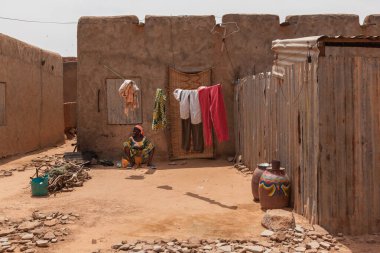 Zinder, Nijer: Afrikalı kadın eski şehir merkezindeki çamurlu evlerde çamaşır yıkıyor