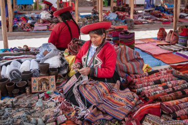 Cuzco, Peru: Quechua kadınları geleneksel yerli kıyafetleriyle pazarda renkli tekstil ürünleri satarak yerel el sanatları hediyelik eşyaları yapıyorlar