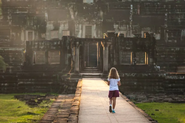 日没の光のジャングルの中で失われた都市の遺跡に離れて歩いて若い女の子 — ストック写真