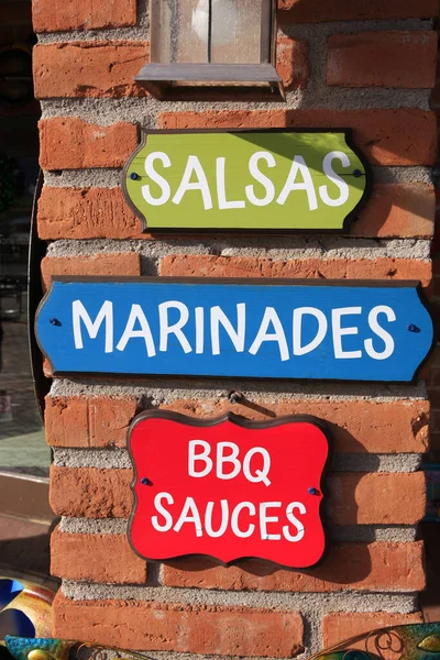 Three brightly painted wall signs with the words Salsa, Marinades and BBQ Sauce written on them