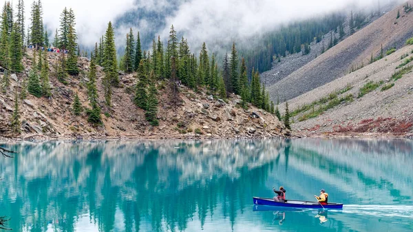 Canoe rowing couple in a beautifully calm waters of Moraine Lake, Banff National Park, Alberta, Canada. — Stock Image Canoe Rowing Couple Beautifully Calm Waters Moraine Lake Banff National Stock Photo