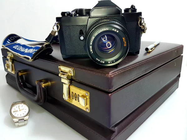 Black Camera Lens Positioned Brown Briefcase Golden Components Accompanied Pen — Stock Photo, Image