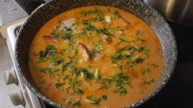 Kız et sosunu ocağın tepsisine koyar.