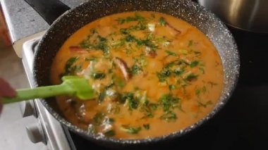 Kız et sosunu ocağın tepsisine koyar.