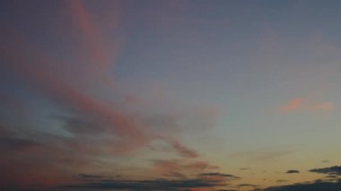 Pembe ve koyu bulutlar sarıdan maviye doğru eğimli bir gökyüzünde yüzerler. Zaman Uygulaması