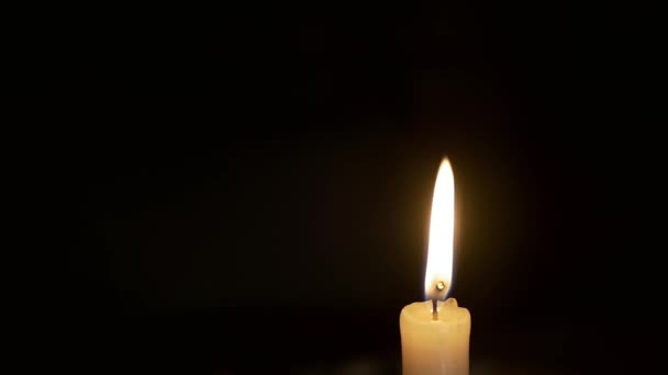 点着的蜡烛在漆黑的黑暗中燃烧，黑色的背景随风飘荡 — 图库视频影像