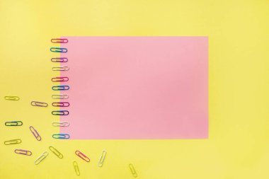 Renkli sabit ofis ekipmanları ya da çalışma rehberi. Kaydı daha organize etmek için renkli bir arkaplanda farklı boyutlarda not defterleri, makaslar, kalemler ve ataçlar var. Yukarıdan bir fotoğraf. Yazı için yer