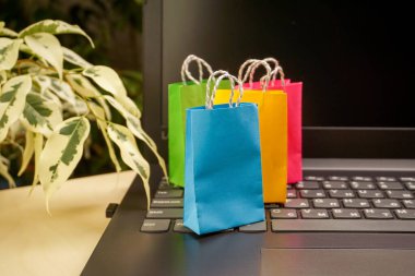 İnternet alışveriş konsepti. Küçük renkli alışveriş çantaları dizüstü bilgisayarda duruyor. Boşluğu kopyala