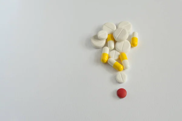 one red pill with many white and yellow  pills on white background. copy space