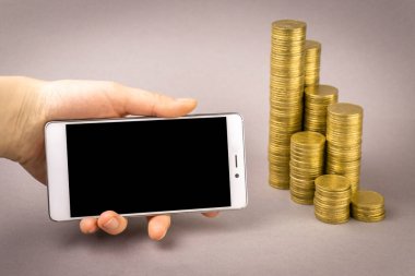 İnternetten alışveriş konsepti. Beyaz akıllı telefon ve gri arka planda bozuk paralar.