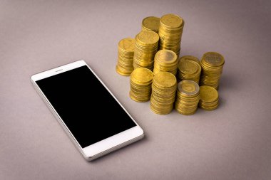 İnternetten alışveriş konsepti. Beyaz akıllı telefon ve gri arka planda bozuk paralar.