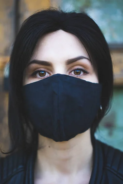 Siyah koruyucu maske solunum cihazıyla koyu renk arka planda kahverengi gözlü genç bir kız. Kendini izole etme, koruma, Coronavirüs, karantina