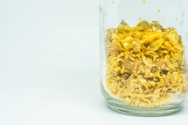 Temiz cam kavanozda kızarmış arpacık soğanları, beyaz arka planda izole edilmiş..