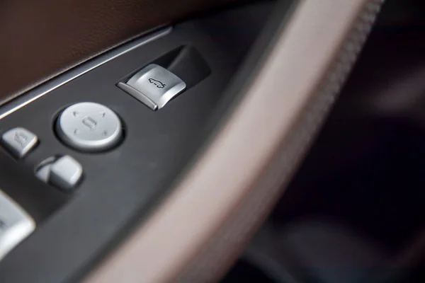 Fermer le bouton de commande ouvrir fermer la porte du coffre sur les conducteurs brun cuir poignée de porte intérieure dans une nouvelle voiture de luxe premium moderne. gros plan, mise au point douce — Photo