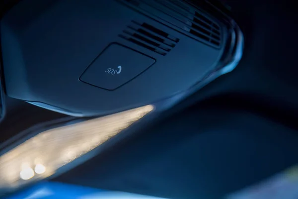 Close-up of the emergency call sos button for contact with call center on the ceiling panel in a modern luxury premium car. close-up, soft focus